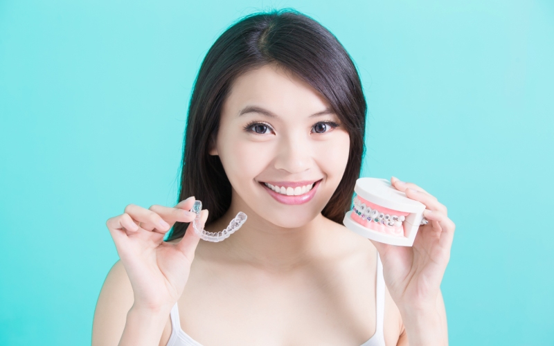woman holding aligner and braces